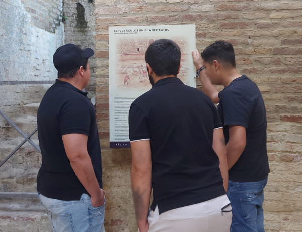 Tres jóvenes leen el panel informativo del anfiteatro romano