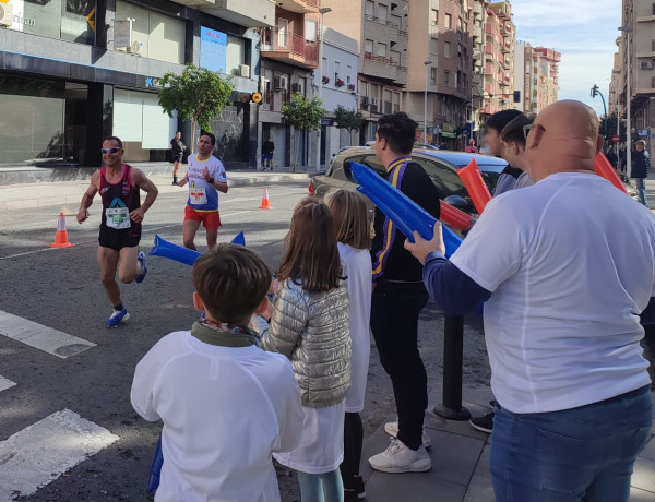 Los niños, niñas y adolescentes de los hogares, junto a un educador, animan a los corredores de la media maratón