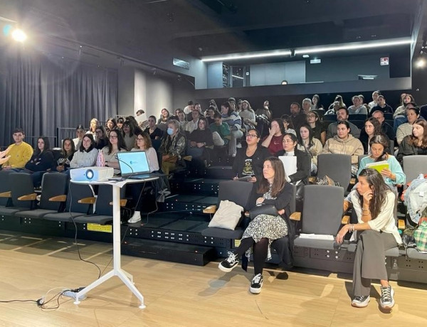 Sala de formación con una ponente explicando y unas 65 personas atendiendo 