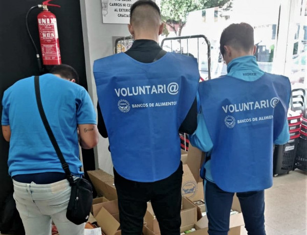 Tres jóvenes del centro de día 'La Botica', junto a las cajas donde recogían los productos