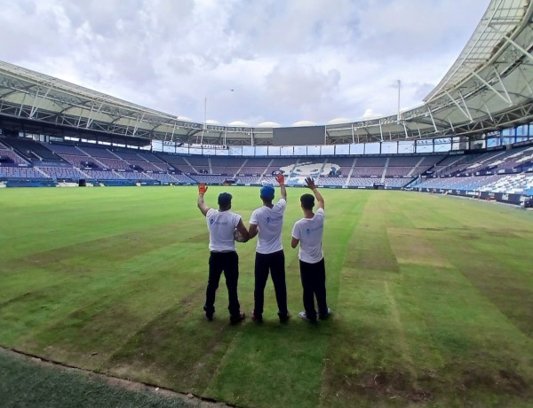 Tres de los jóvenes posan en el estadio con el trabajo casi finalizado