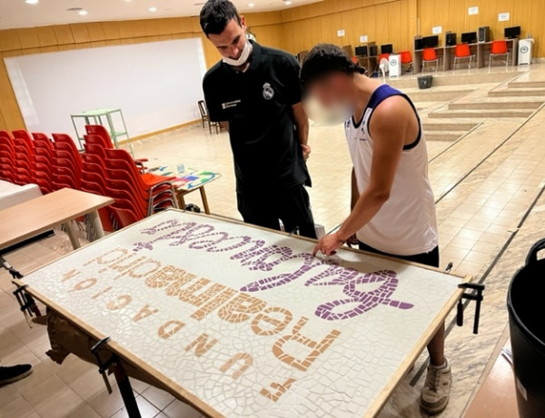 Un joven atendido en la residencia ‘Mariano Ribera’ de Burjassot (Valencia) le entrega un cuadro a un profesional de la Fundación Real Madrid con motivo del final del curso formativo en baloncesto celebrado en el recurso. 