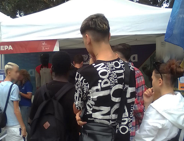 Tres jóvenes observan los puestos informativos de las empresas en la feria