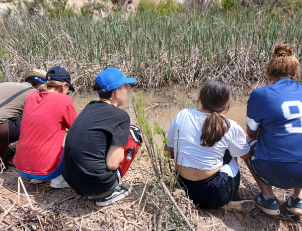 Varios chicos y chicas y su educadora, mientras sueltan gallipatos en el entorno fluvial