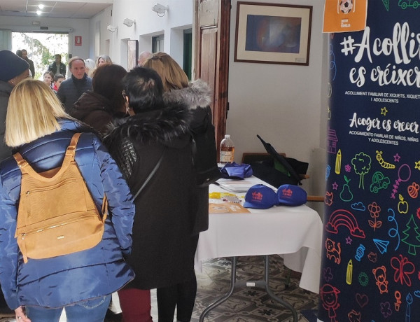 Varias personas pasan junto a la mesa informativa del programa