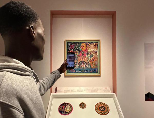 Un joven toma una foto a uno de los cuadros tradicionales de la exposición