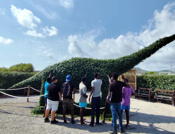 Varios adolescentes contemplan una de las estatuas de dinosaurio