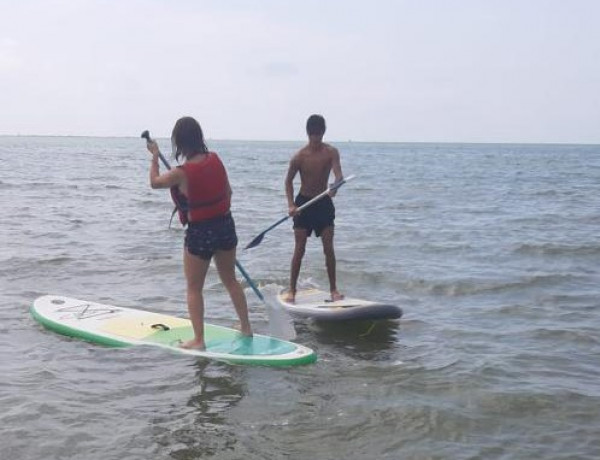 Los jóvenes atendidos en la Unidad de Fomento de la Autonomía ‘Migjorn’ de Tortosa (Tarragona) participan en una jornada de paddle surf
