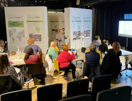 Sala con representantes de ONGDs sentados en mesas redondas y atendiendo a la exposición de un ponente