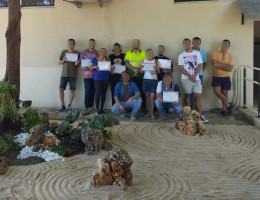 Personas atendidas en Heliotropos muestran su diploma de formación junto al jardín zen del centro