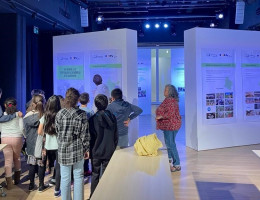 Grupo de niños y niñas viendo unos paneles expositivos con las indicaciones de dos profesionales