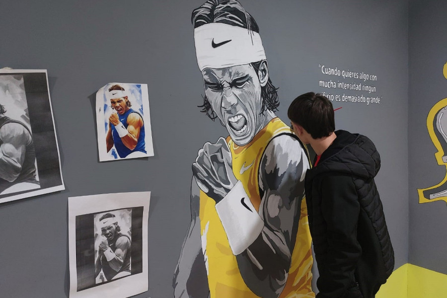 Un joven completa el retrato de Rafa Nadal que decora la sala