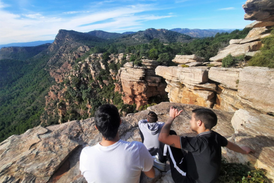 Tres jóvenes descansan al borde de un acantilado en la Ruta de los Calderones