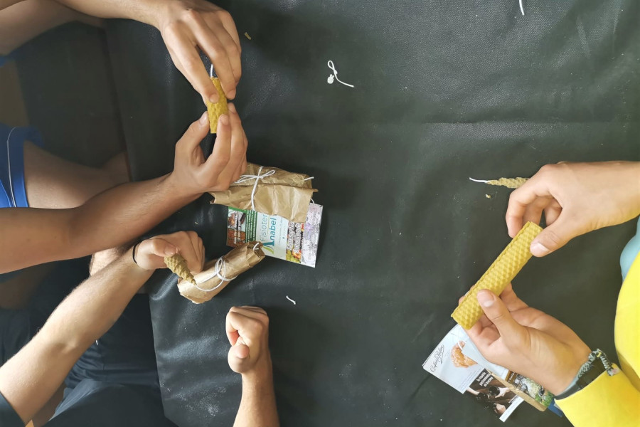 Varios jóvenes aprenden a realizar velas en una actividad del taller