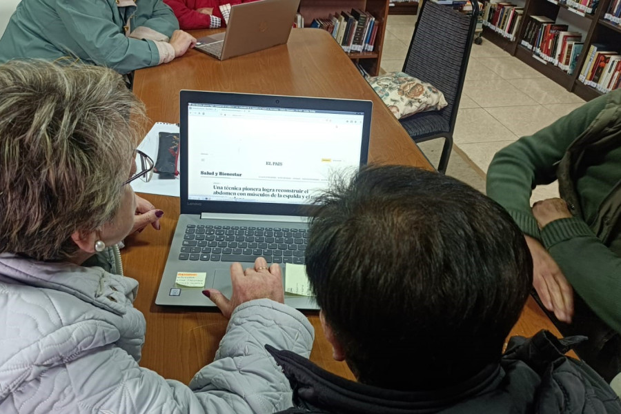 Varias personas mayores utilizan un portátil para leer una noticia en un periódico digital