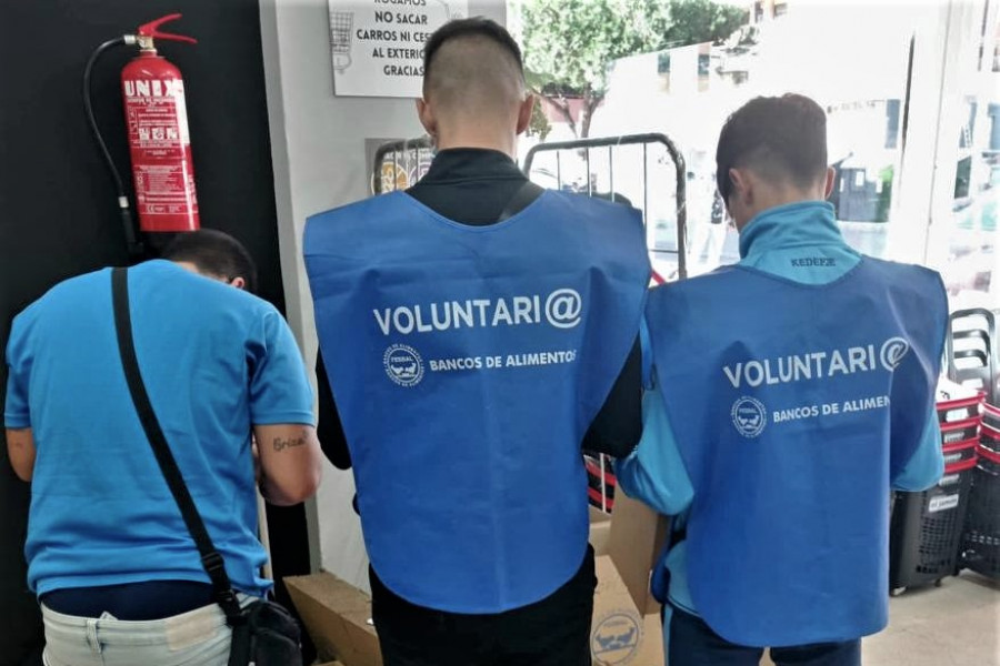 Tres jóvenes del centro de día 'La Botica', junto a las cajas donde recogían los productos