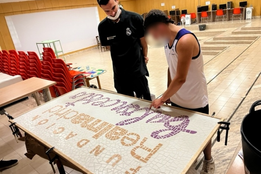 Un joven atendido en la residencia ‘Mariano Ribera’ de Burjassot (Valencia) le entrega un cuadro a un profesional de la Fundación Real Madrid con motivo del final del curso formativo en baloncesto celebrado en el recurso. 