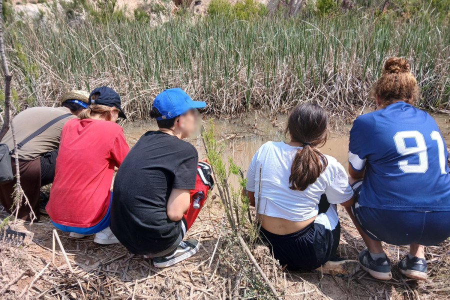 Varios chicos y chicas y su educadora, mientras sueltan gallipatos en el entorno fluvial