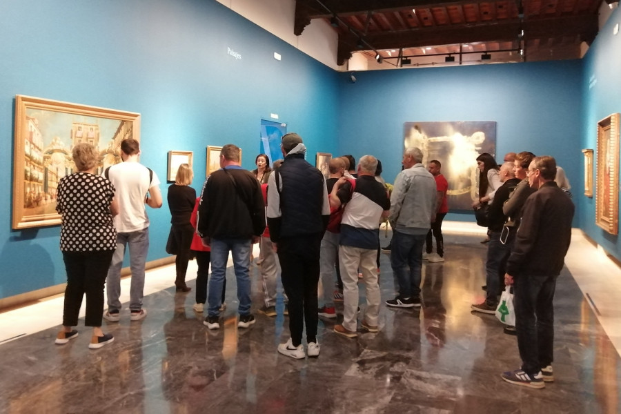El grupo de personas observa una de las obras mientras la guía les explica en qué consiste