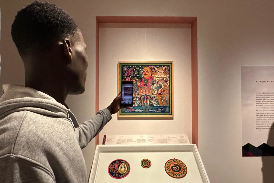 Un joven toma una foto a uno de los cuadros tradicionales de la exposición