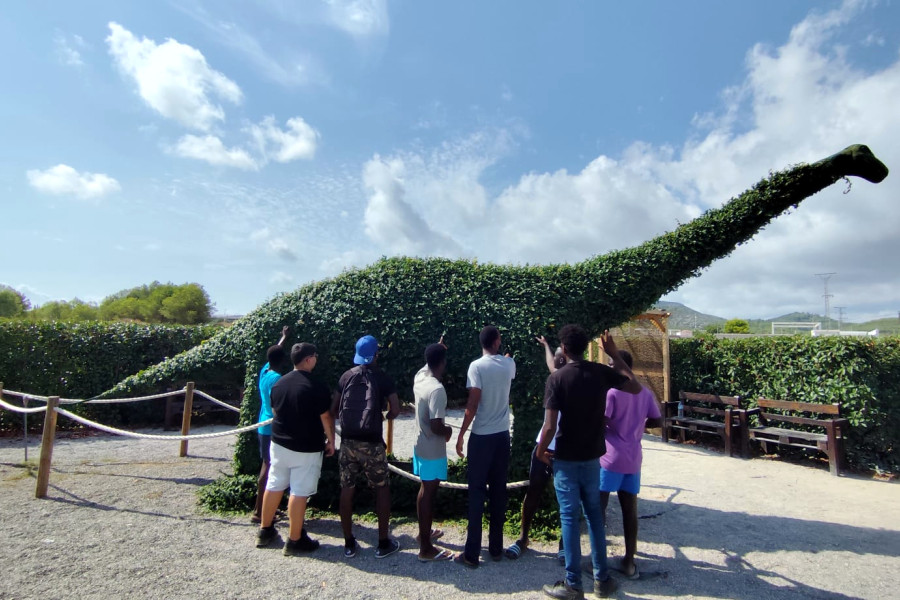 Varios adolescentes contemplan una de las estatuas de dinosaurio