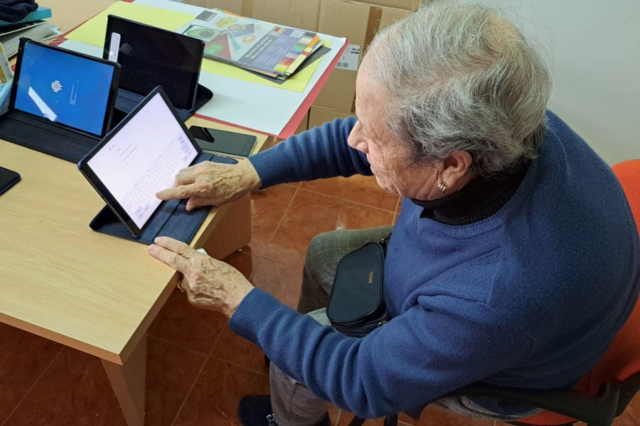 Una mujer de la residencia aprende a utilizar una tablet para buscar información por internet