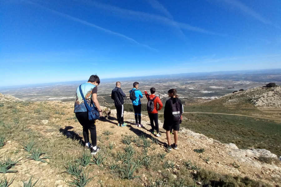 Varios jóvenes y profesionales contemplan el paisaje desde una de las cimas de la ruta