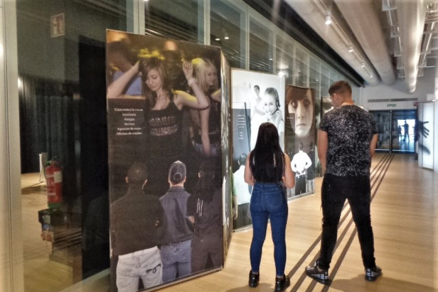 Una chica y un chico posan de espaldas junto a varios de los paneles de la exposición